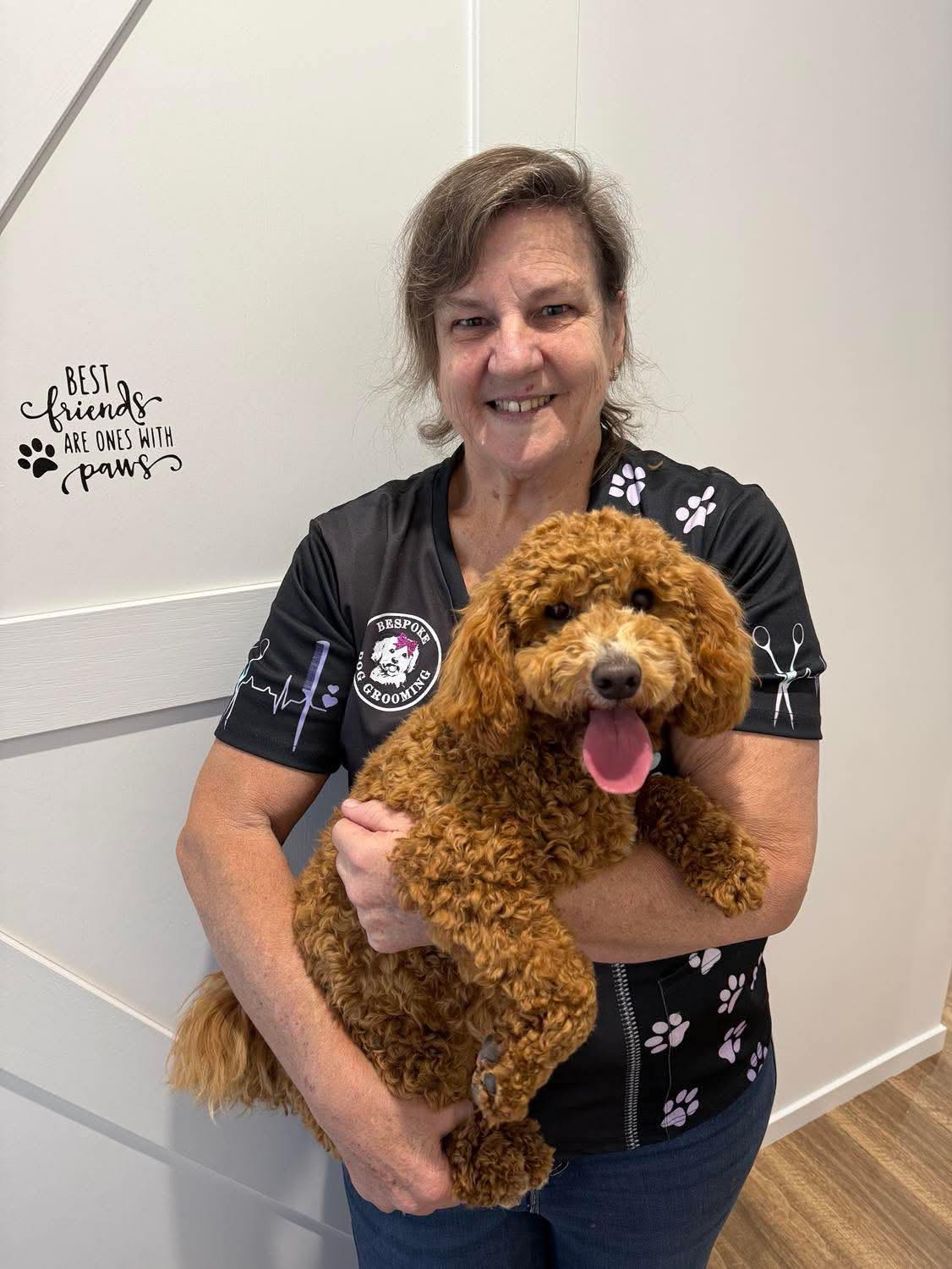 Leona holding a fluffy Cavoodle in her grooming salon